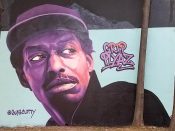 Gus Cutty<br/>2018 - 2024<br/><span style= "font-size: 6pt">33.75102179121776, -84.36754028950284</span> Forward Warrior mural formerly in Cabbagetown Atlanta by Gus Cutty featuring a purple face with a hat