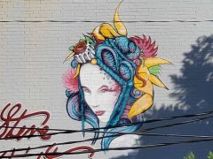 Street art mural formerly in Lindbergh Atlanta by Eric Nine featuring a woman with decorative objects in her hair.