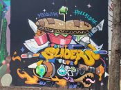 Yoyocam (Cameron Moore) and Leah Abucayan<br/>2024 - 2025<br/><span style= "font-size: 6pt">33.751575723684745, -84.36617246880745</span> Street Art Mural formerly in Cabbagetown Atlanta by Yoyocam (Cameron Moore) and Leah Abucayan featuring a sandwich on a skateboard