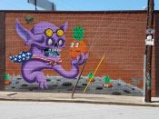 Bigteeff<br/>2016 - 2023<br/><span style= "font-size: 6pt"> 33.79360422813473,-84.4141099601984</span> street art mural formerly in Upper West Side Atlanta by Bigteeff featuring a purple creature holding a pineapple