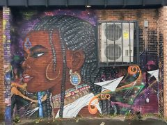 Artist ?<br/>2024 - <br/><span style= "font-size: 6pt">33.739795282695304, -84.41286417610881</span> Street Art Mural in West End Atlanta by an unknown artist featuring a woman with braided hair