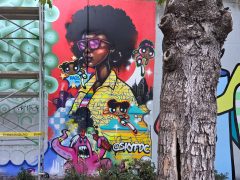 Street Art Mural in Cabbagetown Atlanta by SKIE featuring a person in a yellow graffiti jacket